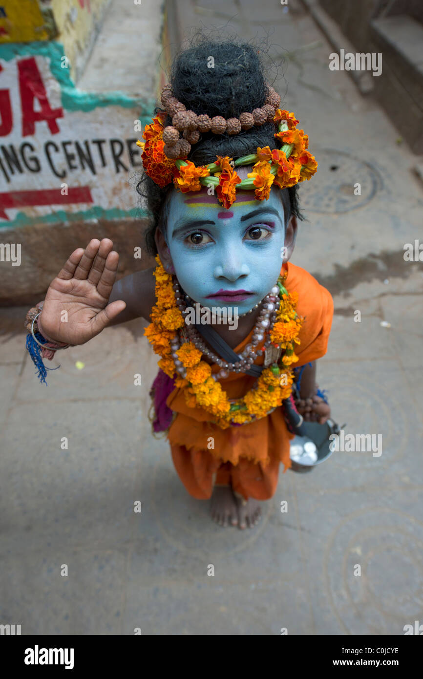 Ragazzo giovane vestito come Shiva mendicare nelle stradine della città vecchia di Varanasi, Uttar Pradesh, India Foto Stock