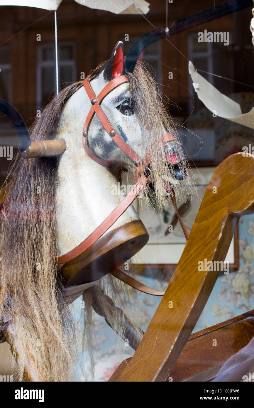 Vecchio cavallo a dondolo in un giocattolo negozio finestra Foto Stock