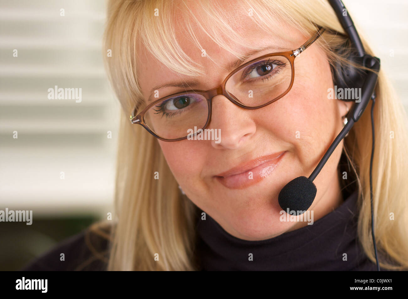 Sorridente imprenditrice colloqui sul suo telefono auricolare. Foto Stock