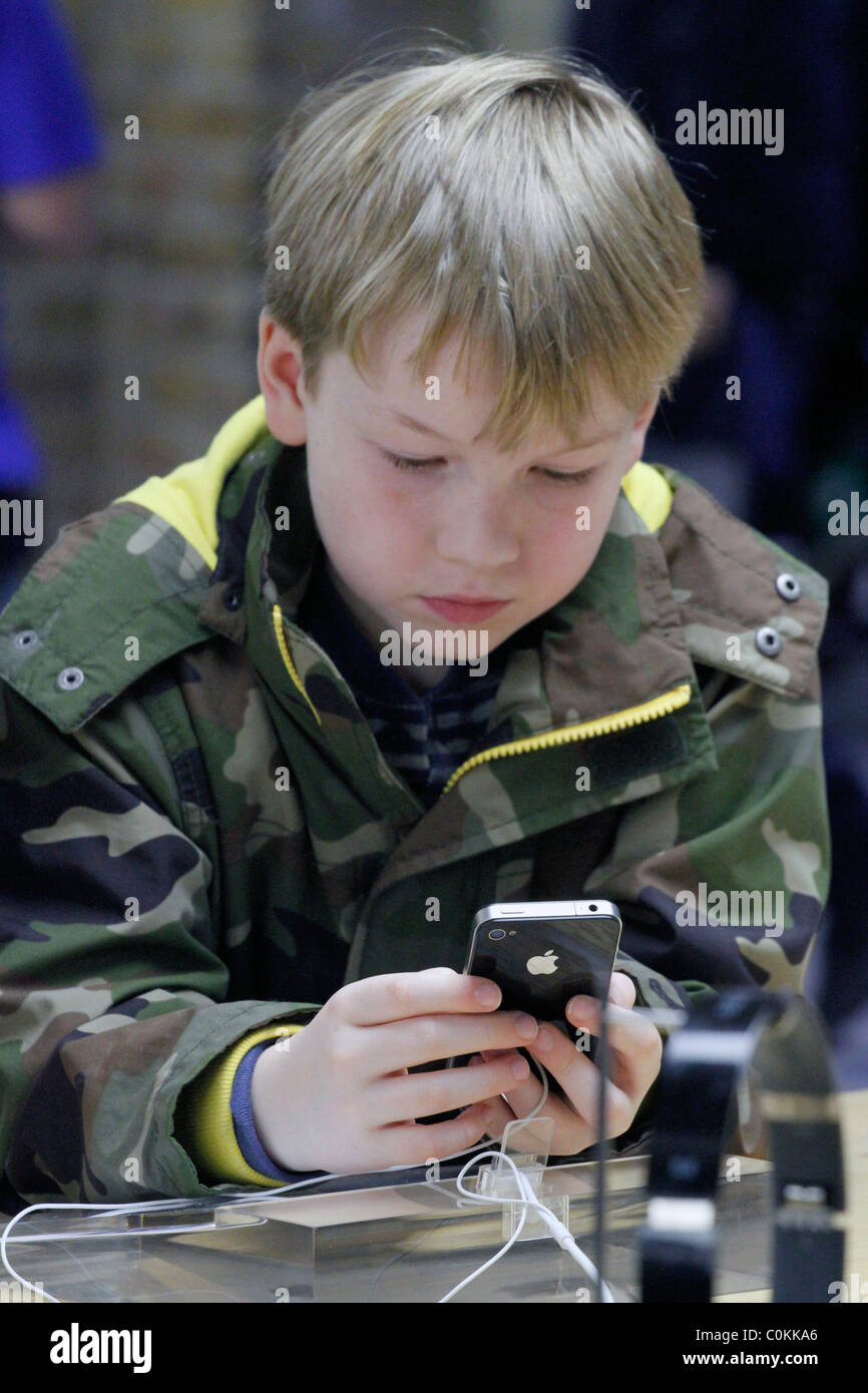 Regno Unito. Ragazzo cerca nuovo iPHONE a un computer MACINTOSH APPLE STORE DI LONDRA Foto Stock