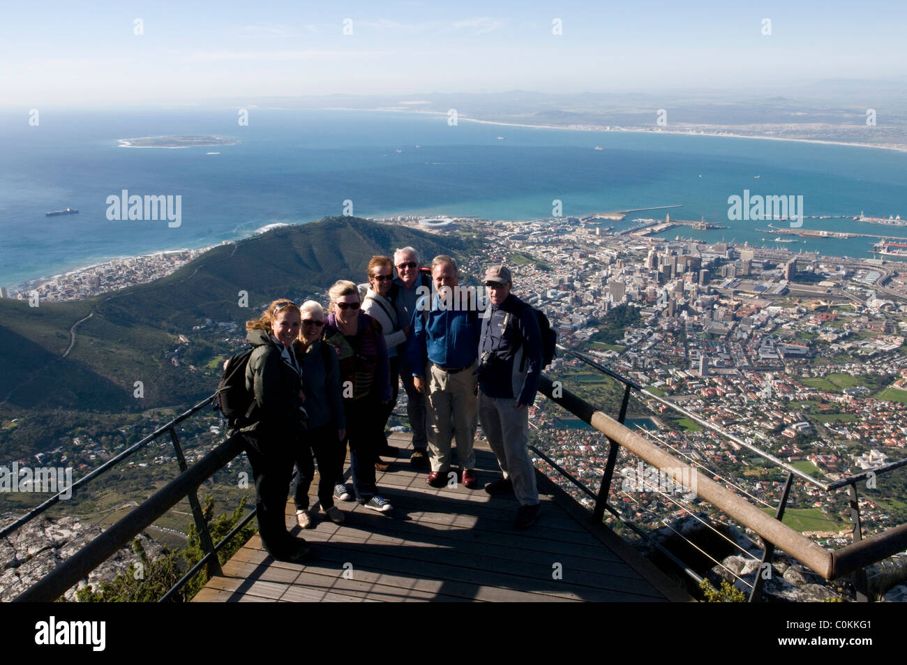 I turisti in piedi su una piattaforma di osservazione che si affaccia su Robben Island e Cape Town, Sud Africa Foto Stock