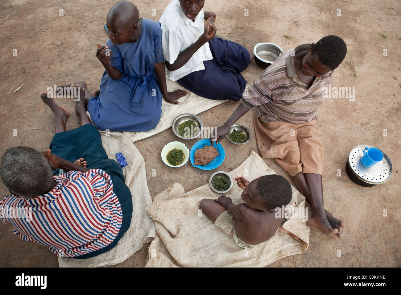 Una famiglia si trova al di fuori di condividere un pasto insieme nel quartiere Amuria, Uganda, Africa orientale. Foto Stock