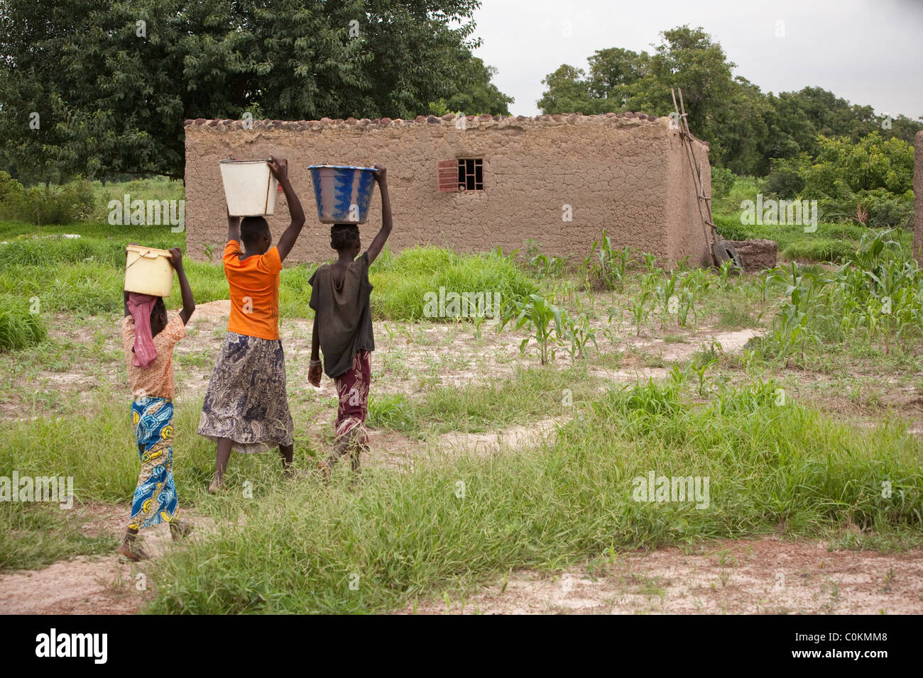 Le ragazze portano a casa di acqua da un pozzo in Safo, Mali, Africa occidentale. Foto Stock