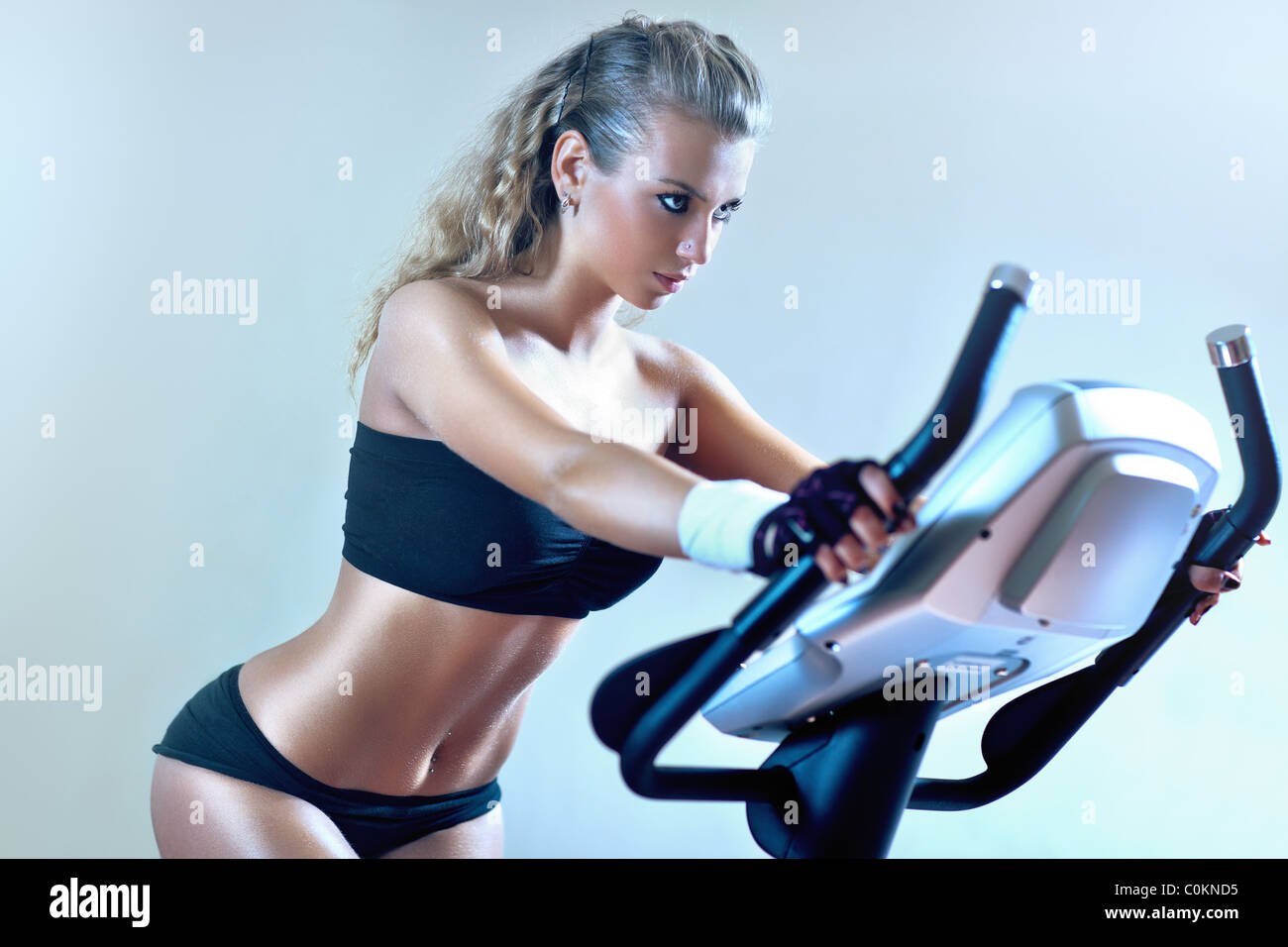Giovane donna sulla cyclette. Morbide tonalità di blu. Foto Stock