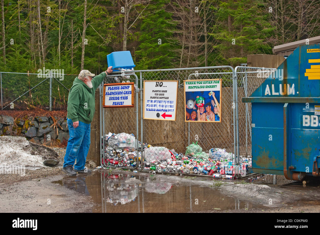 Sitka scuole comunitarie, "Re-cycle Sitka " centro di raccolta in Sitka, Alaska. Alaskan uomo dumping lattine in alluminio in bin. Foto Stock