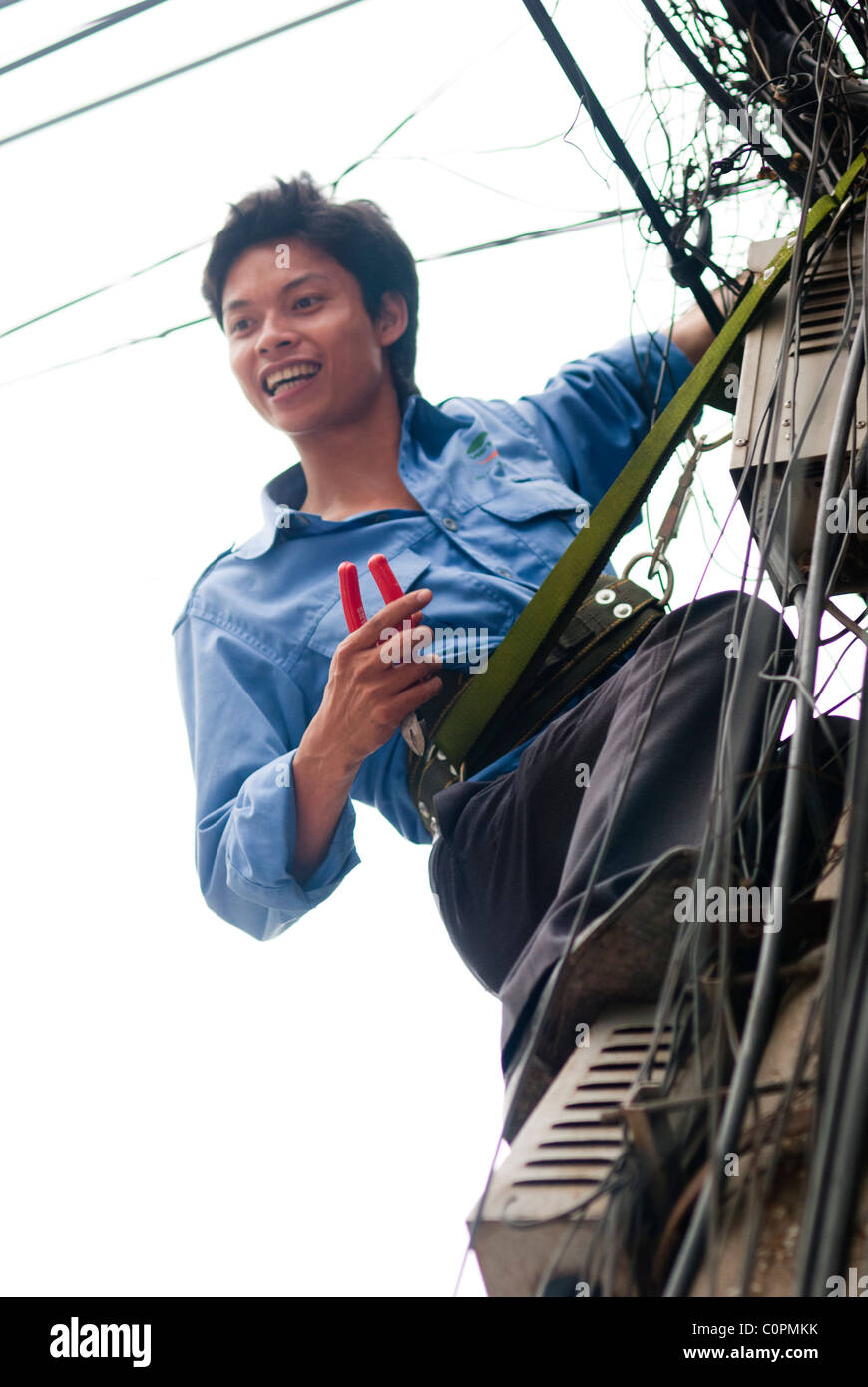 Vietnamita tecnico telefonico di un palo del telegrafo, Hanoi, Vietnam Foto Stock
