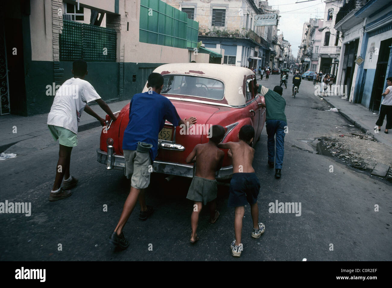 L'Avana. Cuba. Ragazzi spingendo un ripartiti vecchia auto per le strade del centro di Havana. Foto Stock