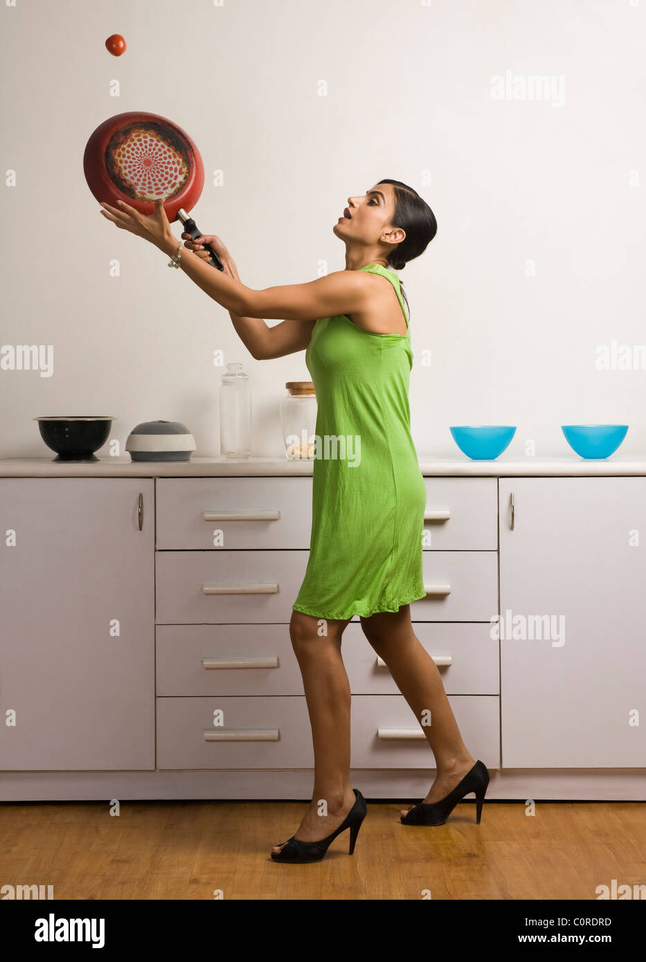 Donna che gioca a tennis con una padella e un pomodoro Foto Stock