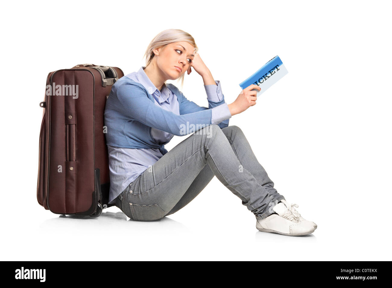 Un turista ragazza seduta vicino una valigia con un biglietto in mano Foto Stock