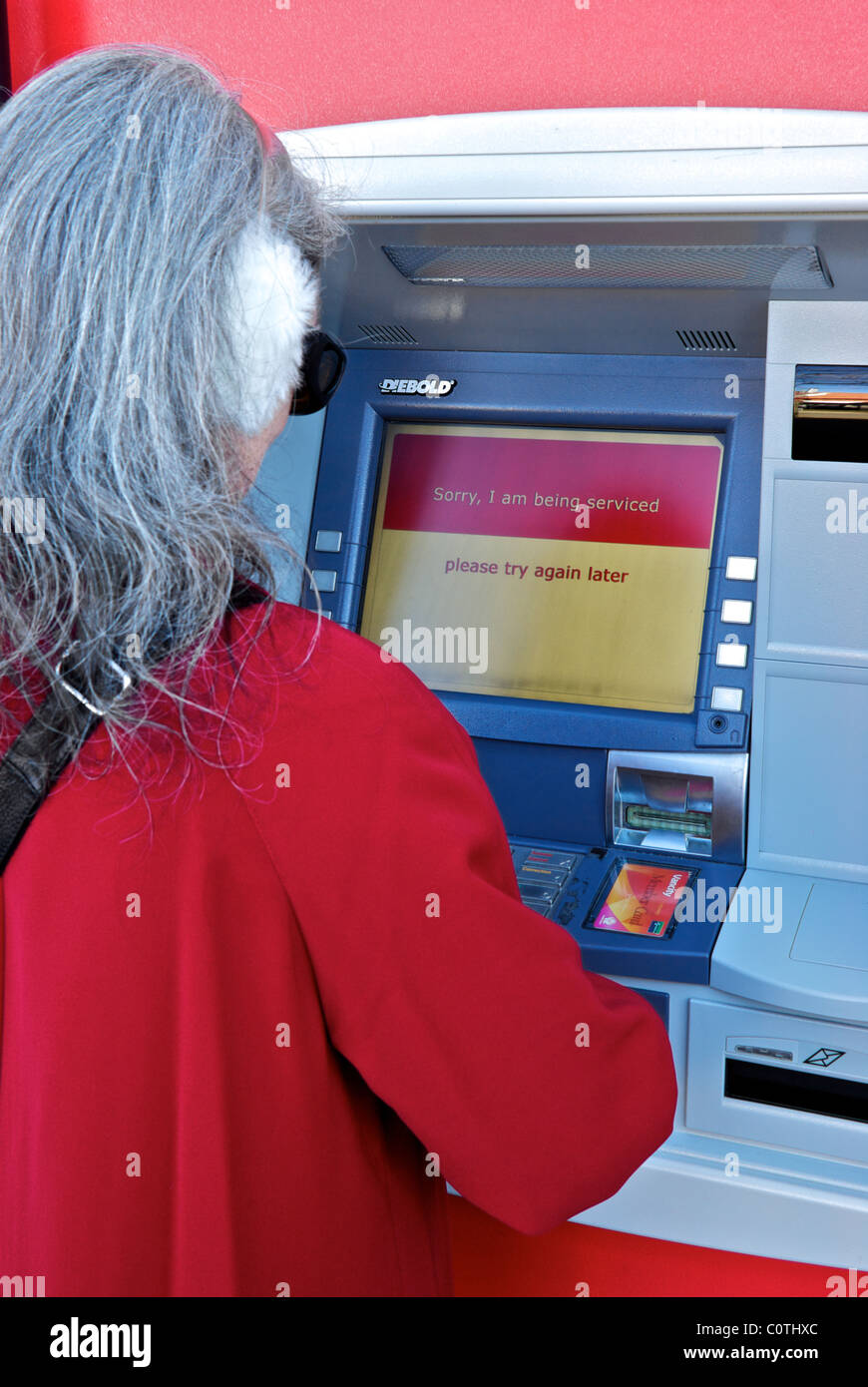 Donna colore rosso umettare la lettura temporanee interruzioni di servizio messaggio sulla banca bancomat schermo LCD Foto Stock