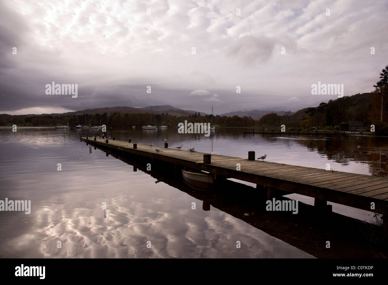 Cielo nuvoloso le riflessioni e il molo sul Lago di Windermere, Ambleside, Lake District, Cumbria, England, Regno Unito Foto Stock