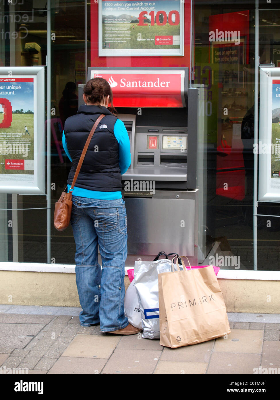 Giovane donna di ottenere denaro da un ramo di Santander ATM, Barnstaple, Devon, Regno Unito Foto Stock