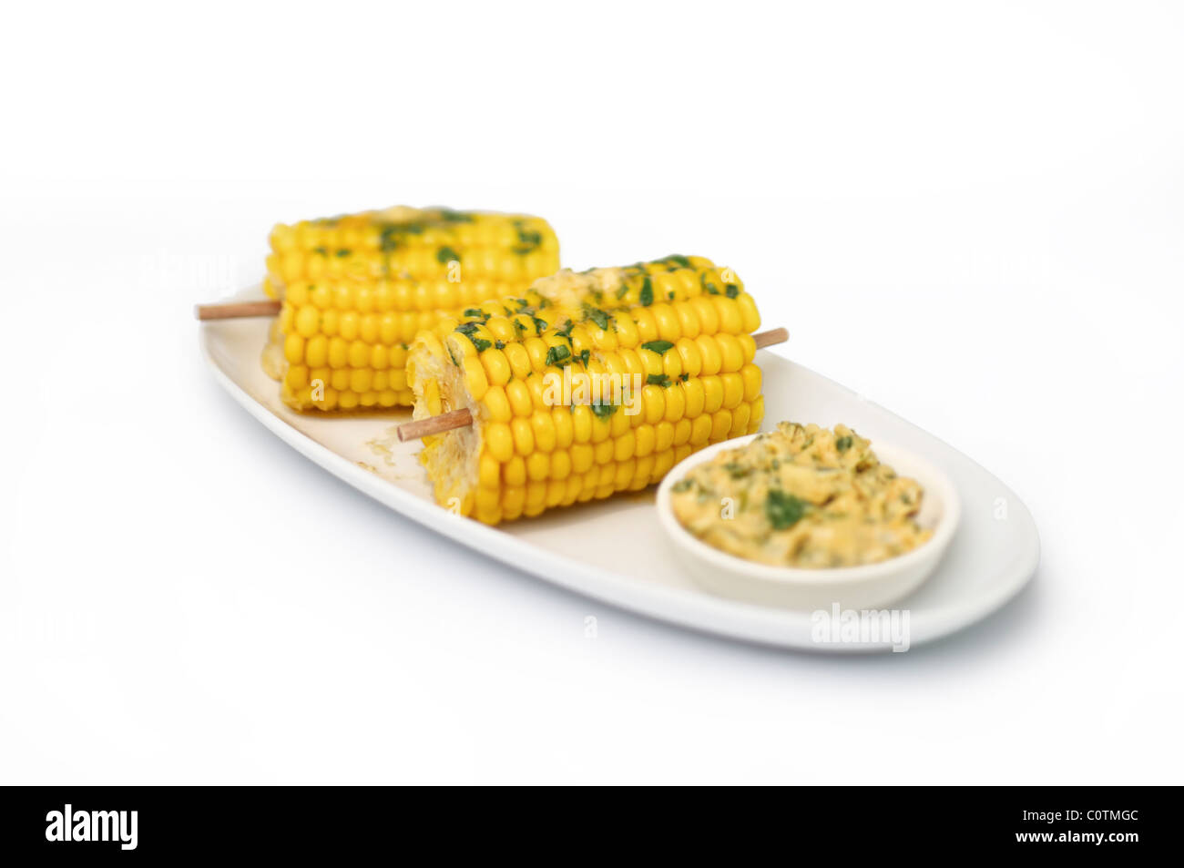 Una piastra con sulla pannocchia di mais e un piatto di lato, con percorso di esclusione. Foto Stock