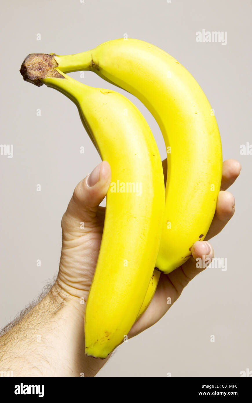 Grappolo di banane tenuto a mano isolato su un grigio/sfondo bianco con spazio per il testo o sfinestratura. Foto Stock