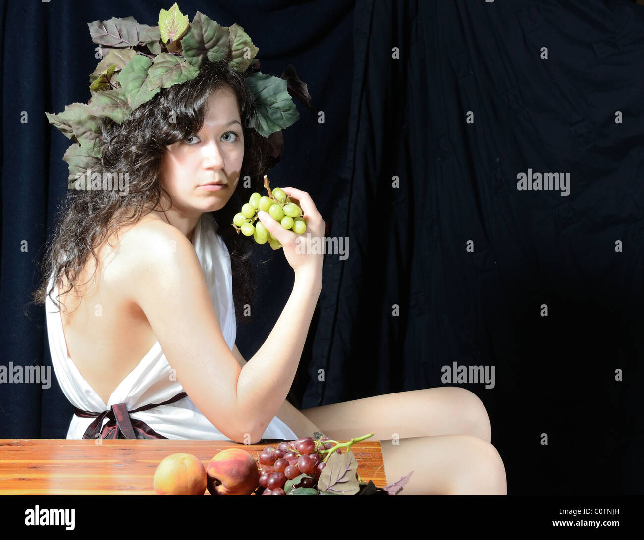 Una bella donna vestita come Dionisio il dio greco della vendemmia. Foto Stock