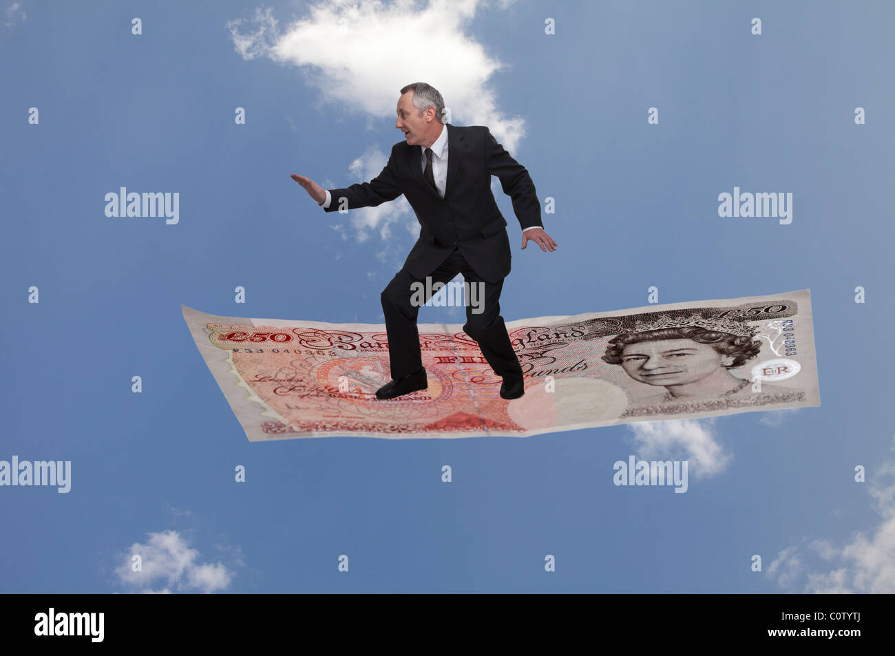 Uomo d'affari 'Flying' su una banca di Inghilterra 50 pound contro un cielo blu con nuvole bianche Foto Stock