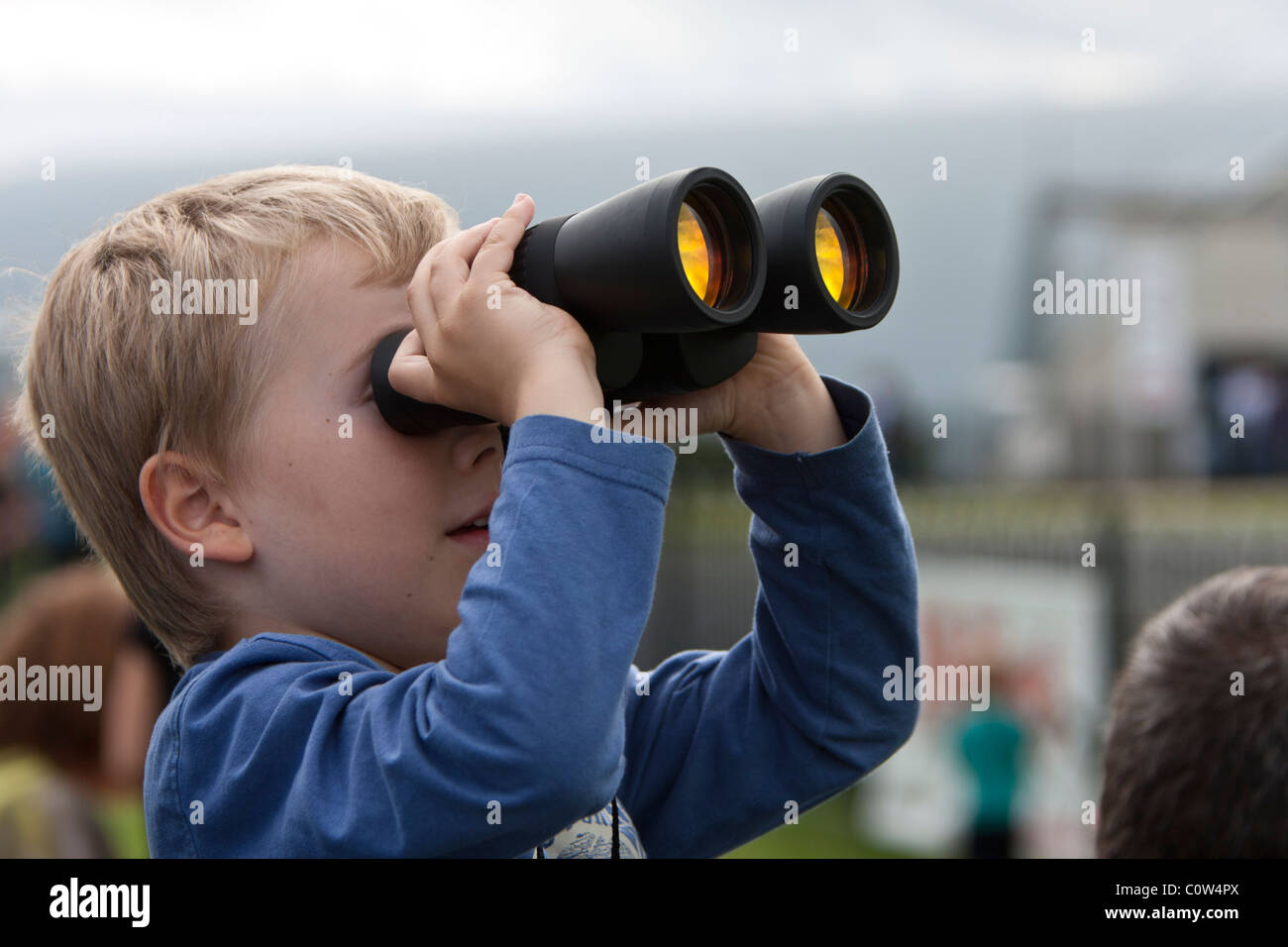 Ragazzo guardando gli aeroplani con un binocolo in corrispondenza di un'esibizione aerea Foto Stock