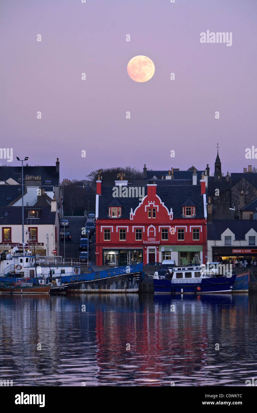 Porto di Stornoway con la Luna Piena al tramonto. Foto Stock