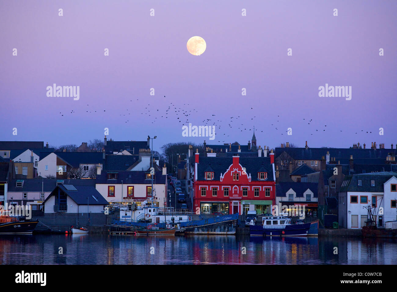 Porto di Stornoway con la Luna Piena al tramonto. Foto Stock