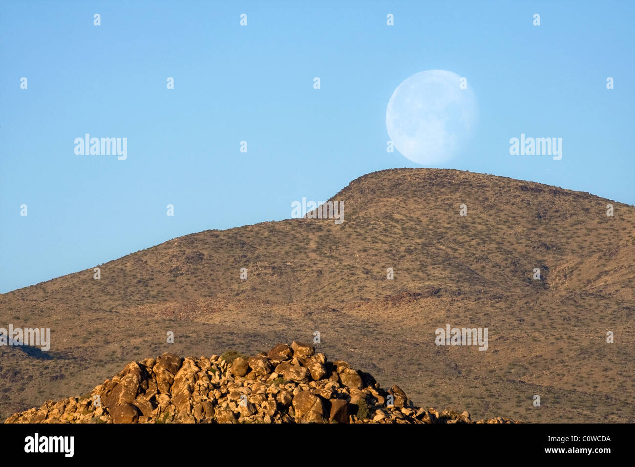 La luna sorge su una montagna nel deserto di Mojave, California. Foto Stock