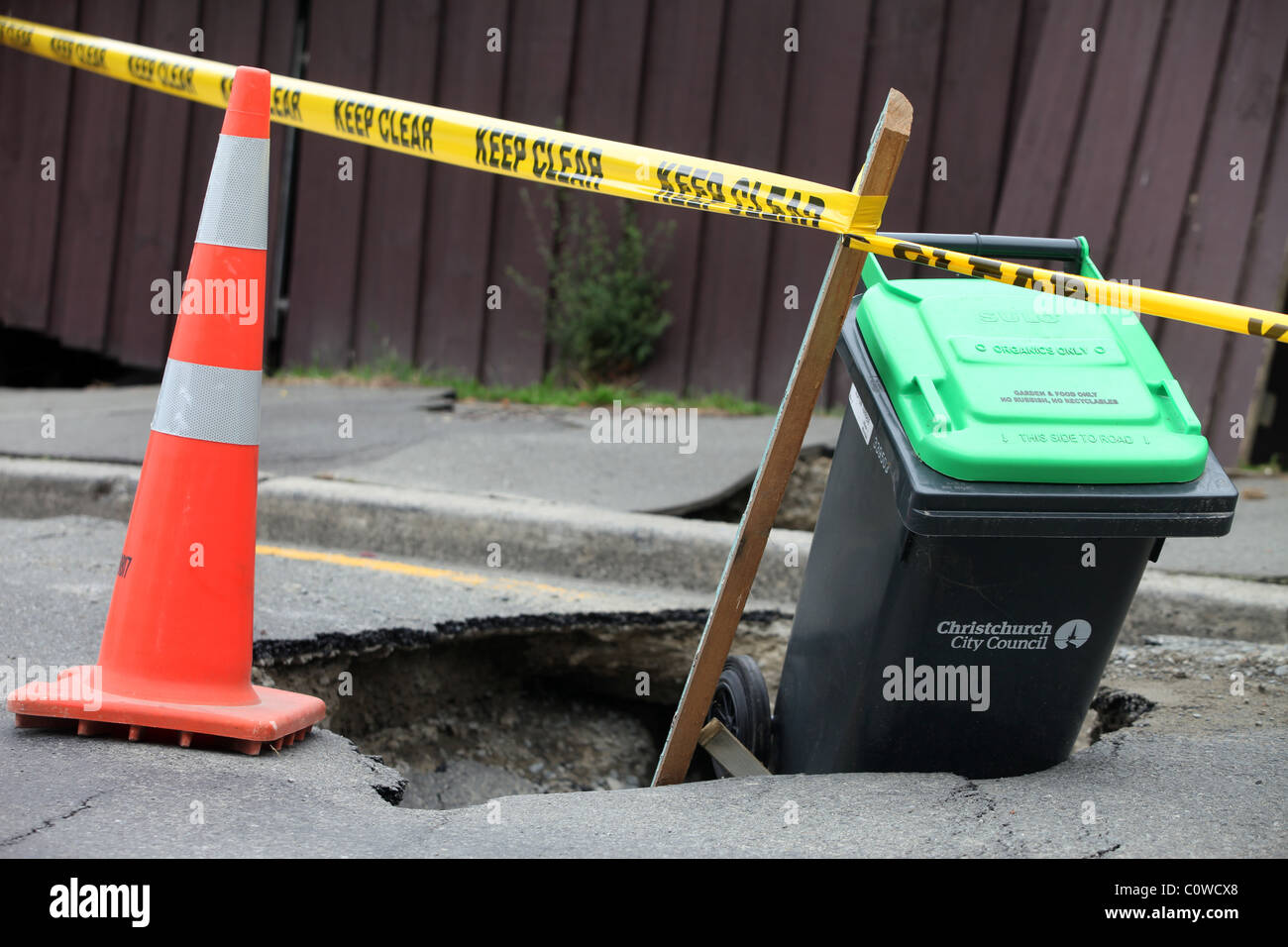 Un bidone con ruote è utilizzata per contrassegnare un foro in strada dopo il 6.3 terremoto di magnitudine, Christchurch, Nuova Zelanda Foto Stock
