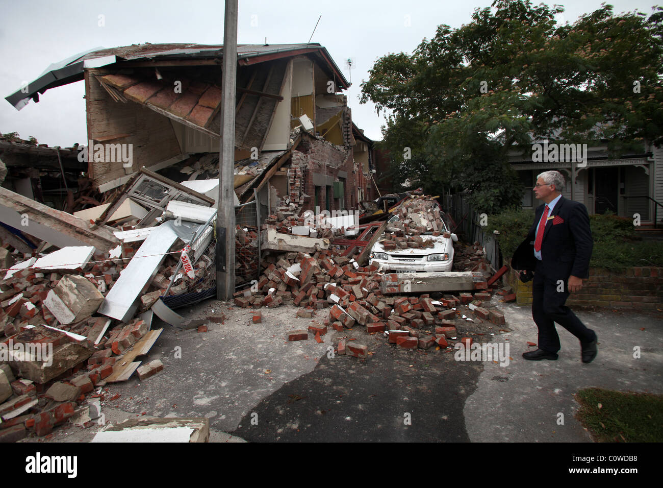 Uomo che cammina passato una proprietà in rovina sulla Bealey Avenue, Christchurch, Nuova Zelanda, dopo il 6.3 terremoto di magnitudine Foto Stock