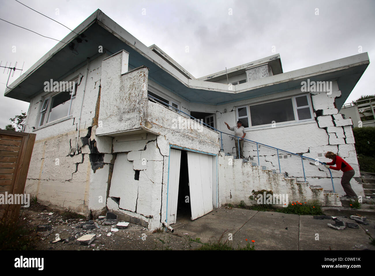 I residenti di fretta per rimuovere la proprietà da un male casa danneggiata in Sumner, Christchurch, seguendo il 6.3 terremoto di magnitudine. Foto Stock