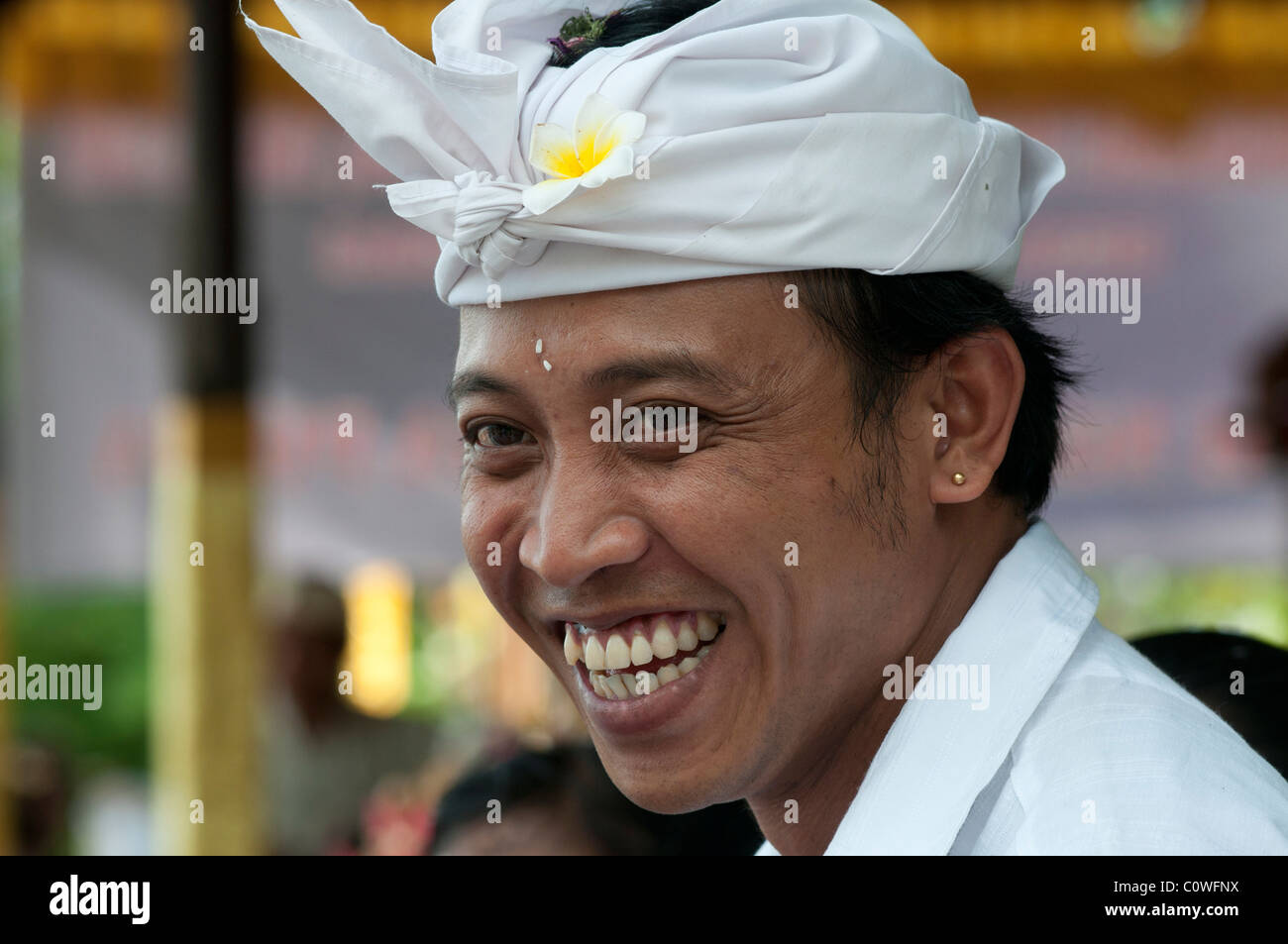 Sorridente uomo balinese che indossa il tradizionale abito da testa udeng ad un festival del tempio a Padang Bai nella parte orientale di Bali in Indonesia Foto Stock