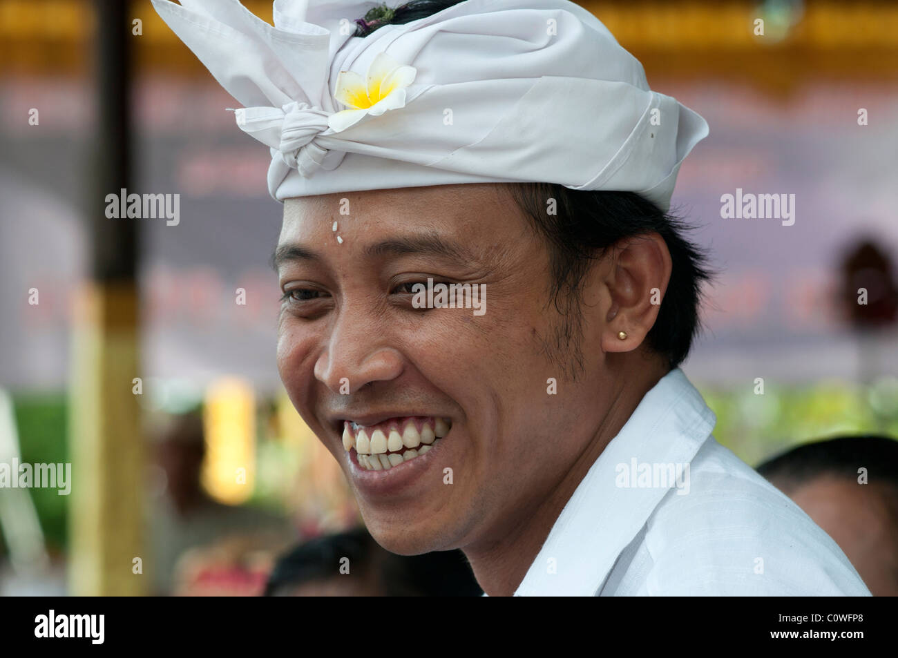 Sorridente uomo balinese che indossa il tradizionale abito da testa udeng ad un festival del tempio a Padang Bai nella parte orientale di Bali in Indonesia Foto Stock