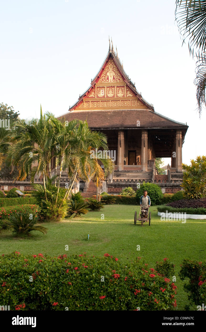 Giardiniere Falciare il prato, Haw Pha Kaew, ora un museo di arte e antichità, Vientiane, Laos Foto Stock