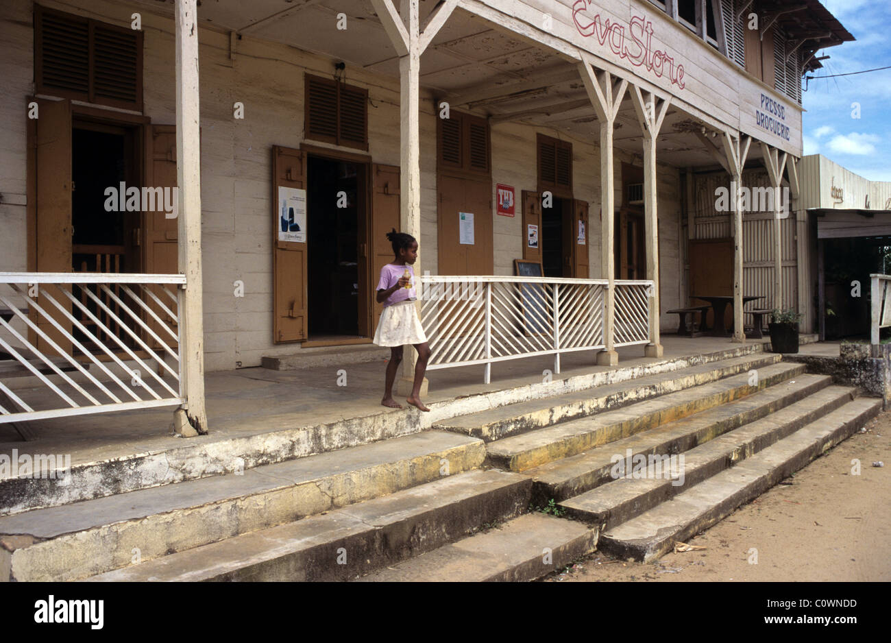 Ragazza malgascio fuori di un legno-telaio o di legno General Store o di un negozio di convenienza sulla strada principale di Sambava, Madagascar Foto Stock