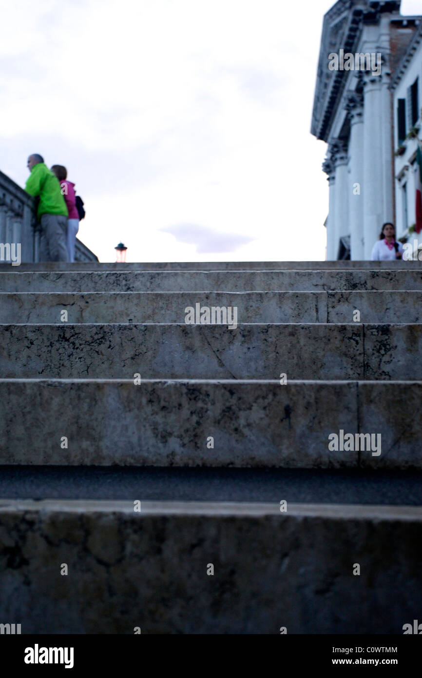 Turisti in cima di passi a Venezia Italia, indossa giacche in verde e rosso. Foto Stock