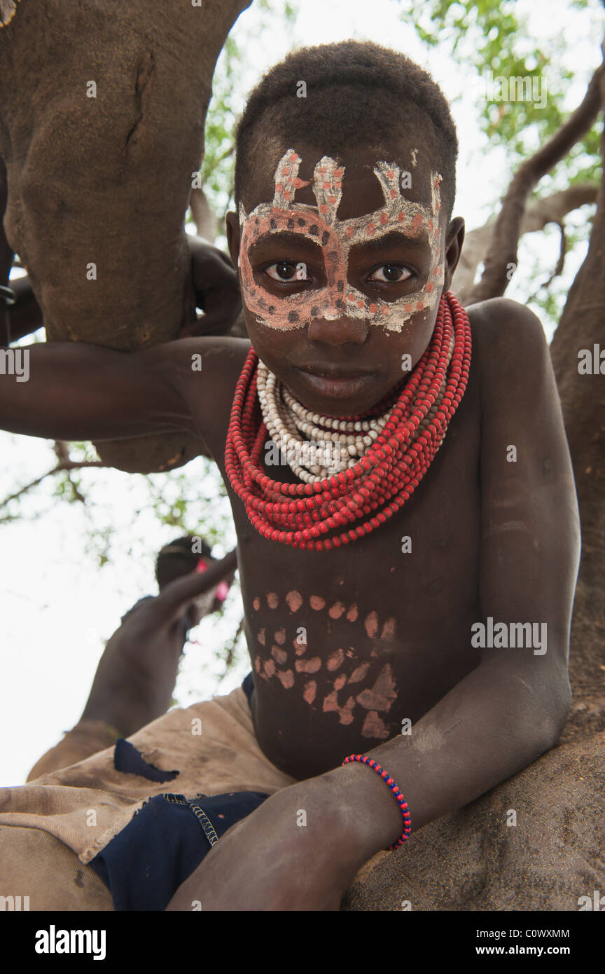 Karo ragazzo con volto dipinti in un albero, Omo river valley, sud Etiopia Foto Stock