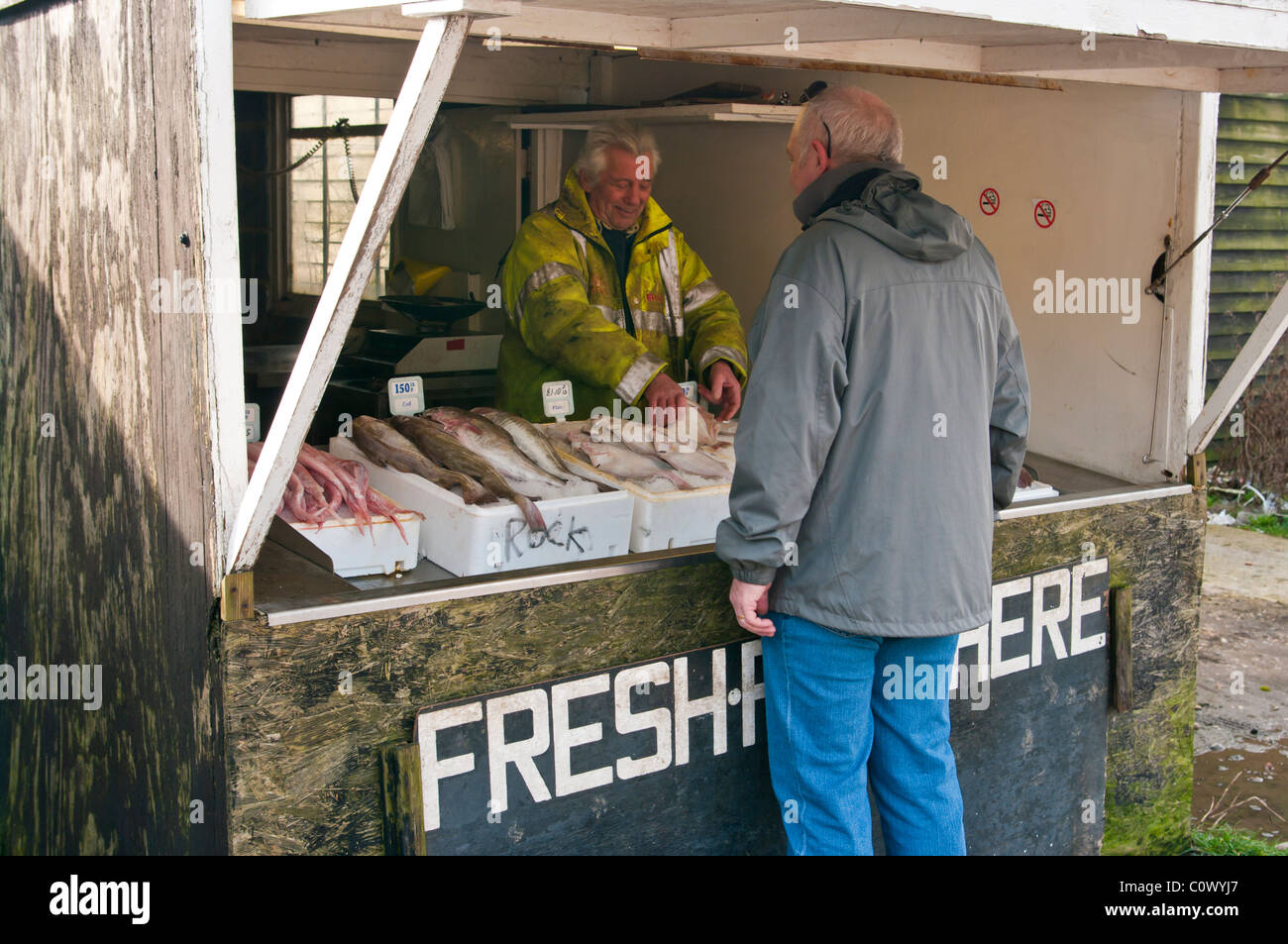 Pescatore che serve un cliente in un pesce fresco in stallo Hastings East Sussex England Foto Stock
