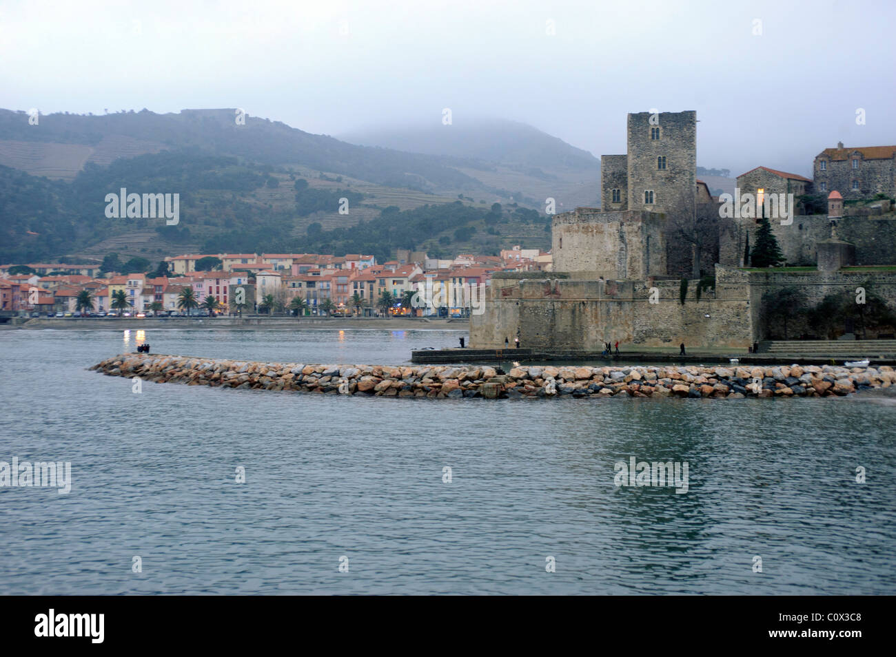 Veduta del porto di Collioure Francia in inverno al tramonto con nuvole e montagne (fondo) Foto Stock