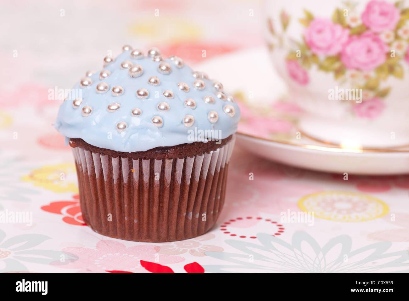 Blue Cup cake con tazza da tè sullo sfondo con fiori. Foto Stock