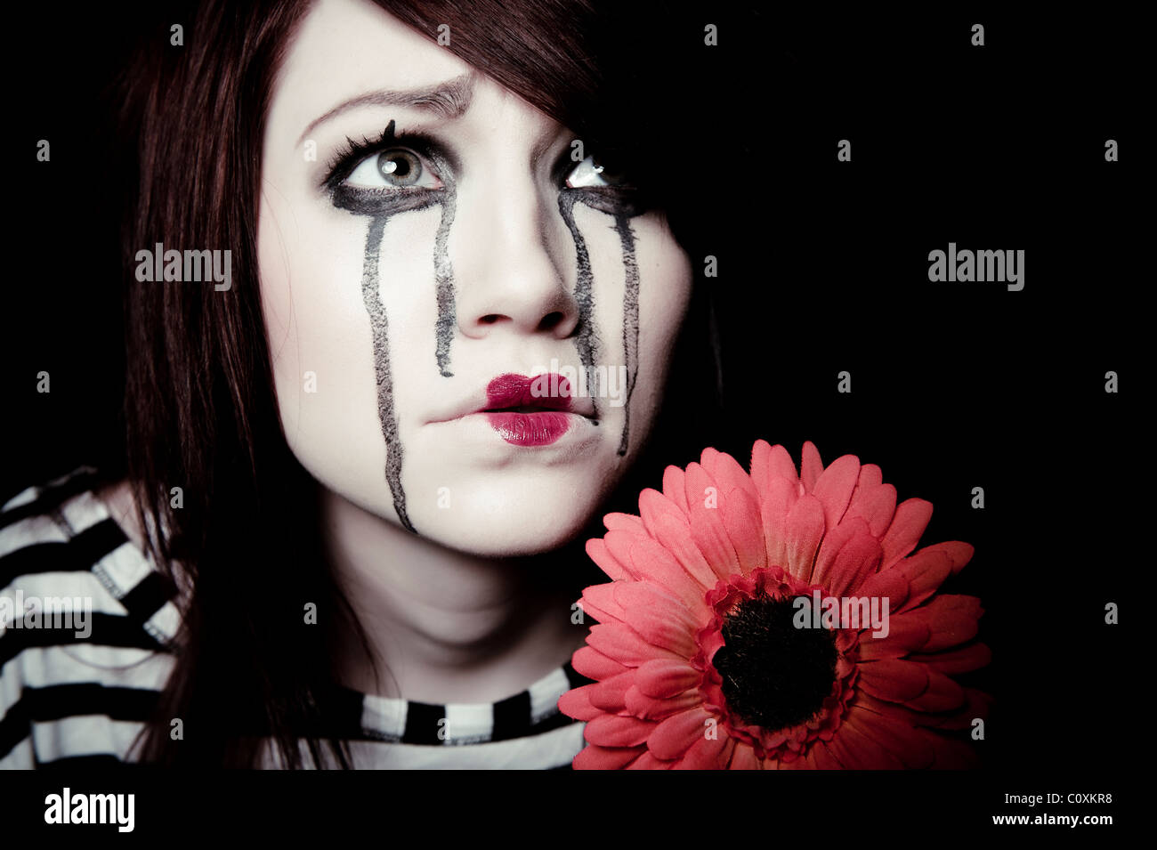 Un triste femmina clown mime con un fiore rosso Foto Stock