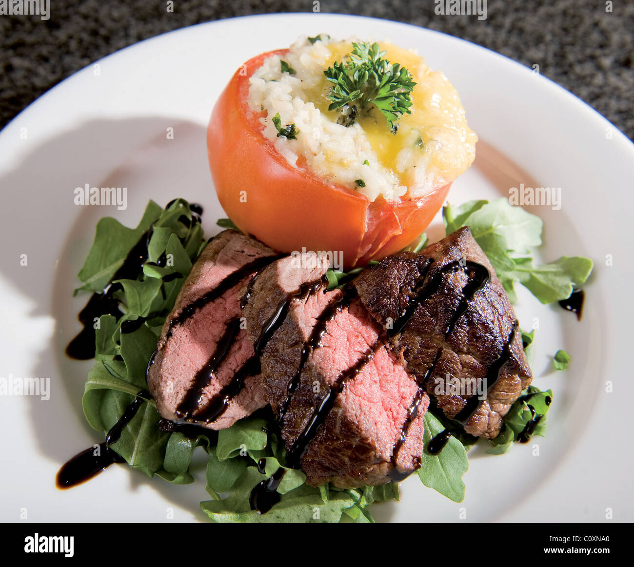 Pan fried Lakeland di manzo con formaggio blu risotto farcito di pomodoro di manzo con rucola e basamic insalata di smalto Foto Stock