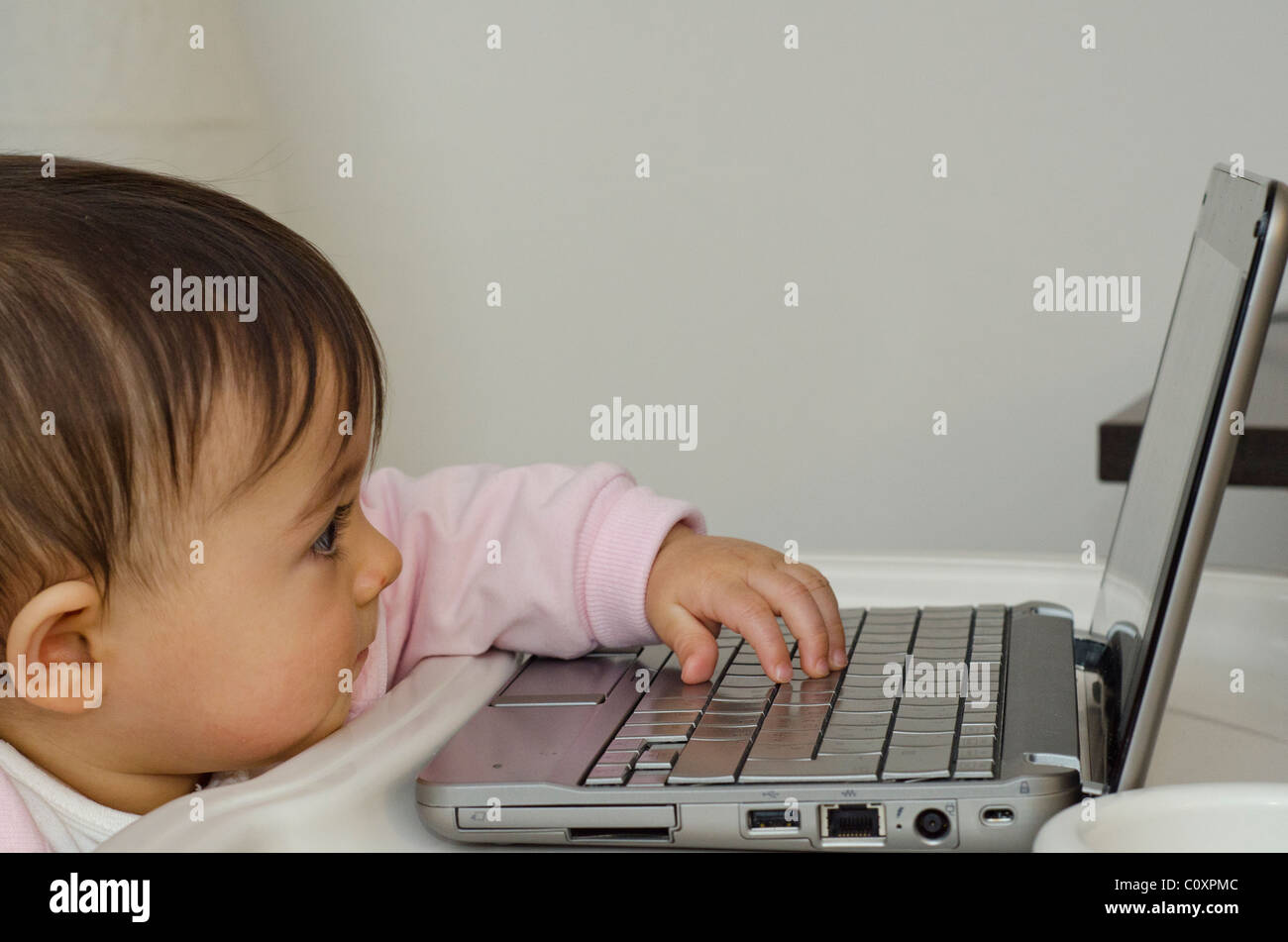 1 anno Baby girl cercando di utilizzare il suo netbook, Italia Foto Stock