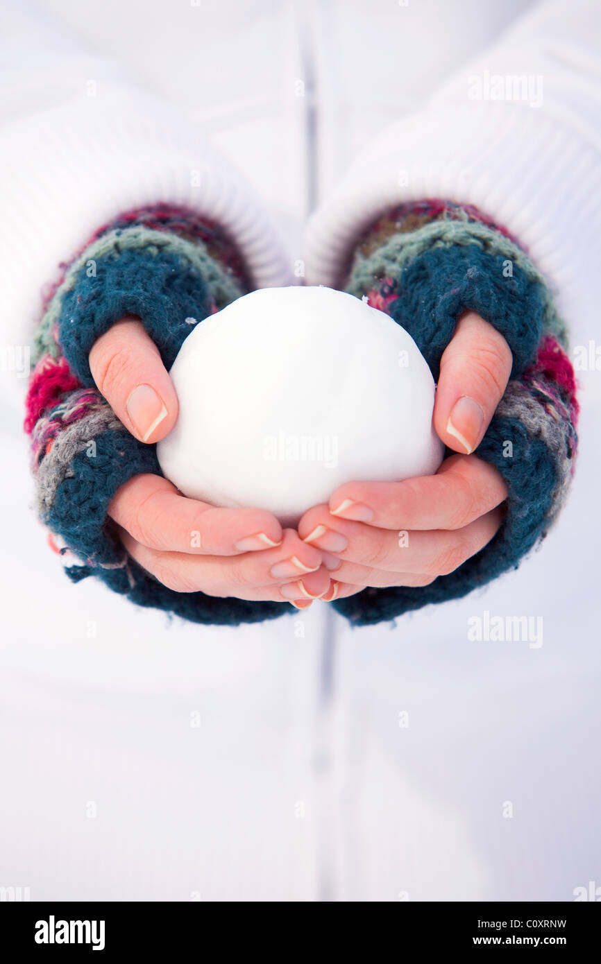 Una ragazza che indossa guanti senza dita tenendo una palla di neve Foto Stock