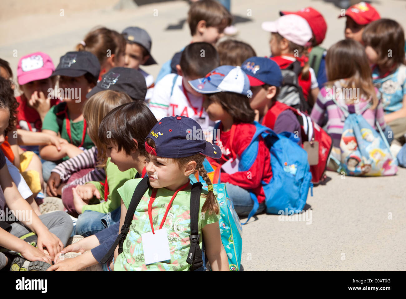 Gruppo di bambini seduti sul marciapiede durante il viaggio scolastico. Barcellona Spagna. Foto Stock