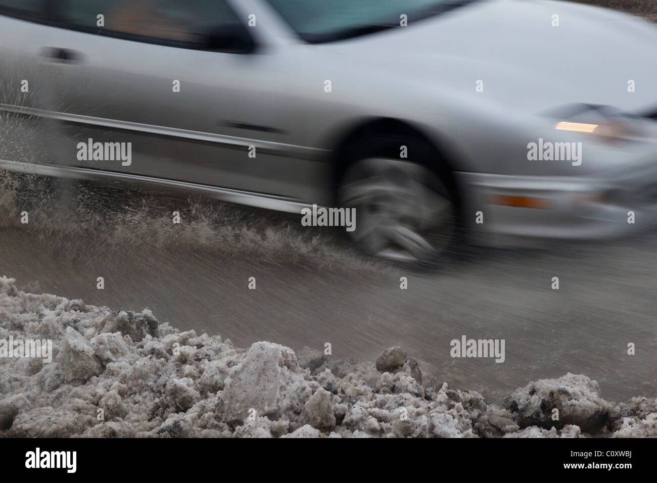 Slush vola come unità di traffico su una neve e neve melt coperto sezione di strada. Foto Stock