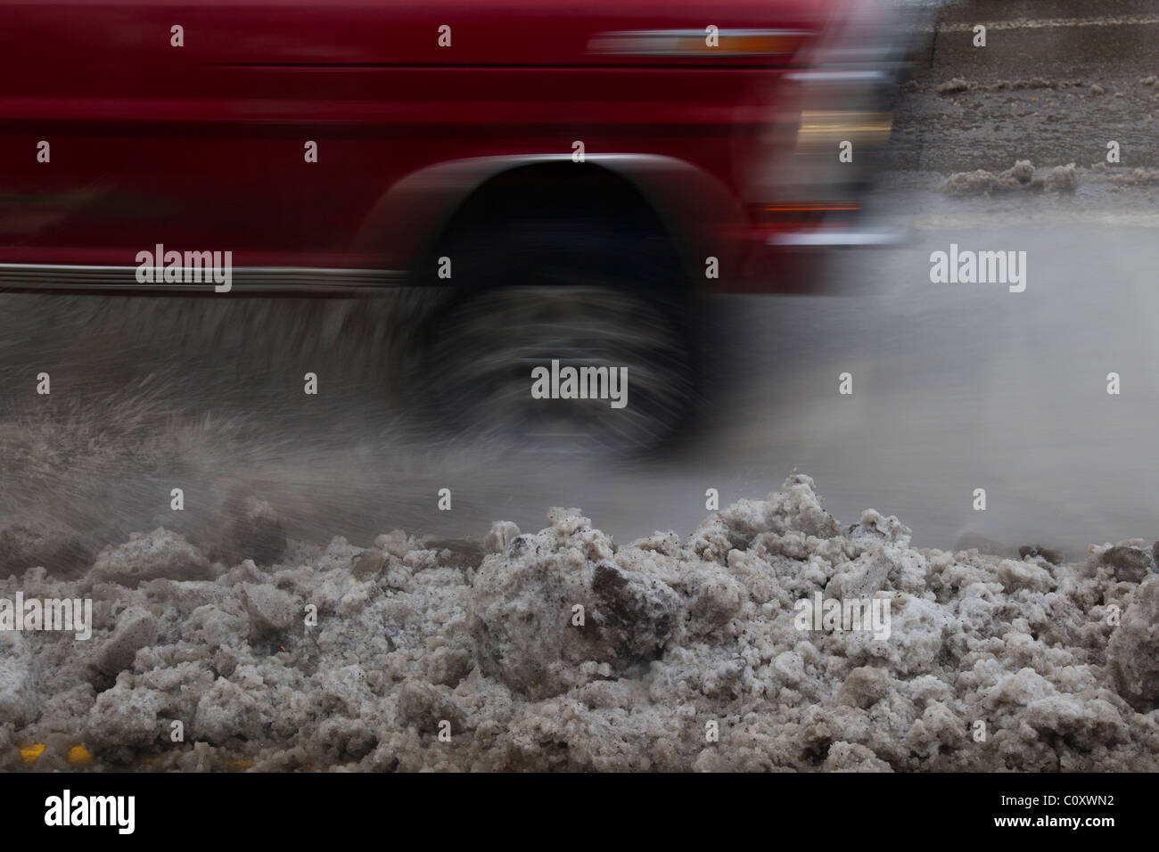 Slush vola come unità di traffico su una neve e neve melt coperto sezione di strada. Foto Stock