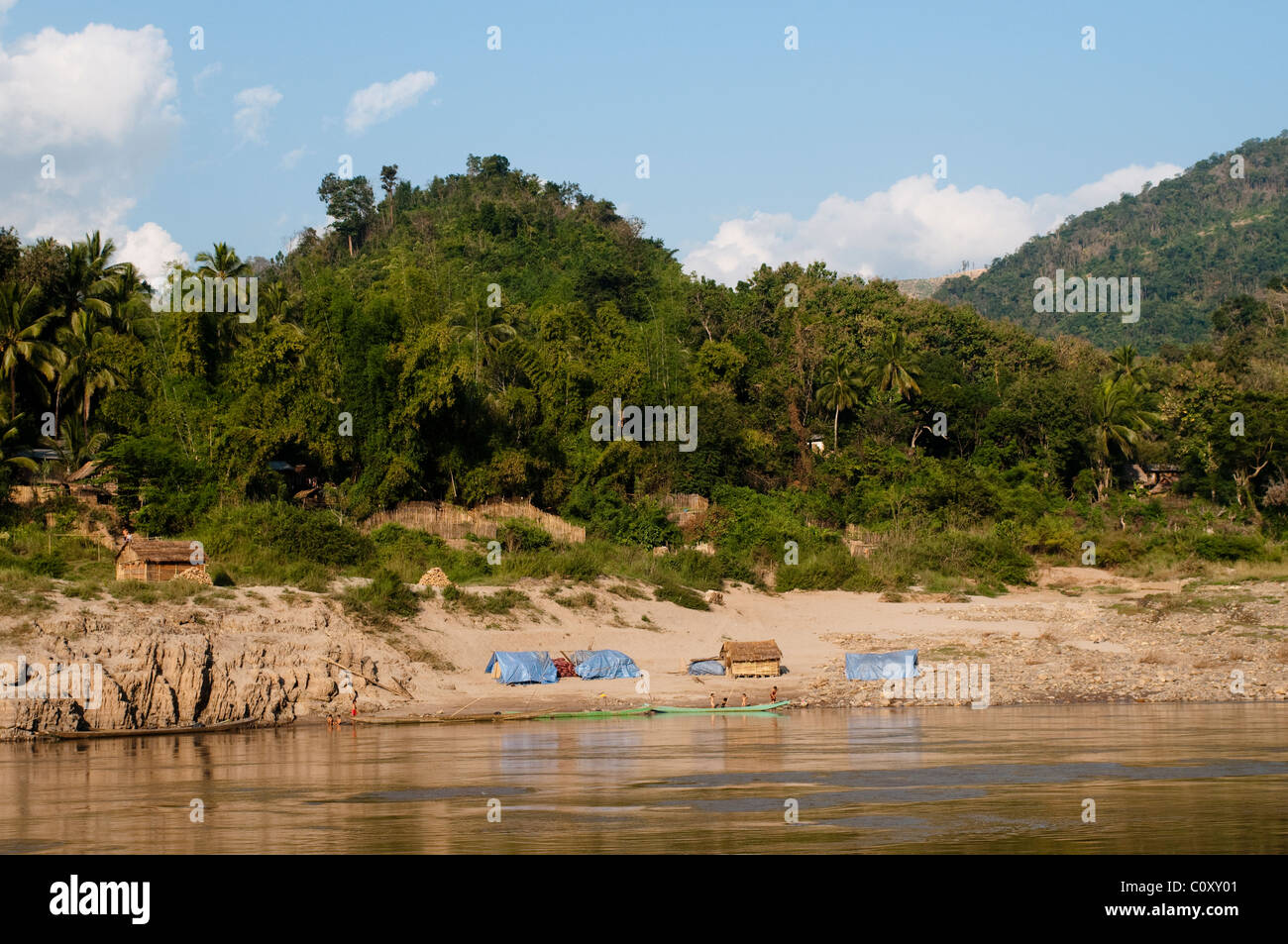 Banca tropicale del fiume Mekong e il villaggio di capanne, Laos Foto Stock