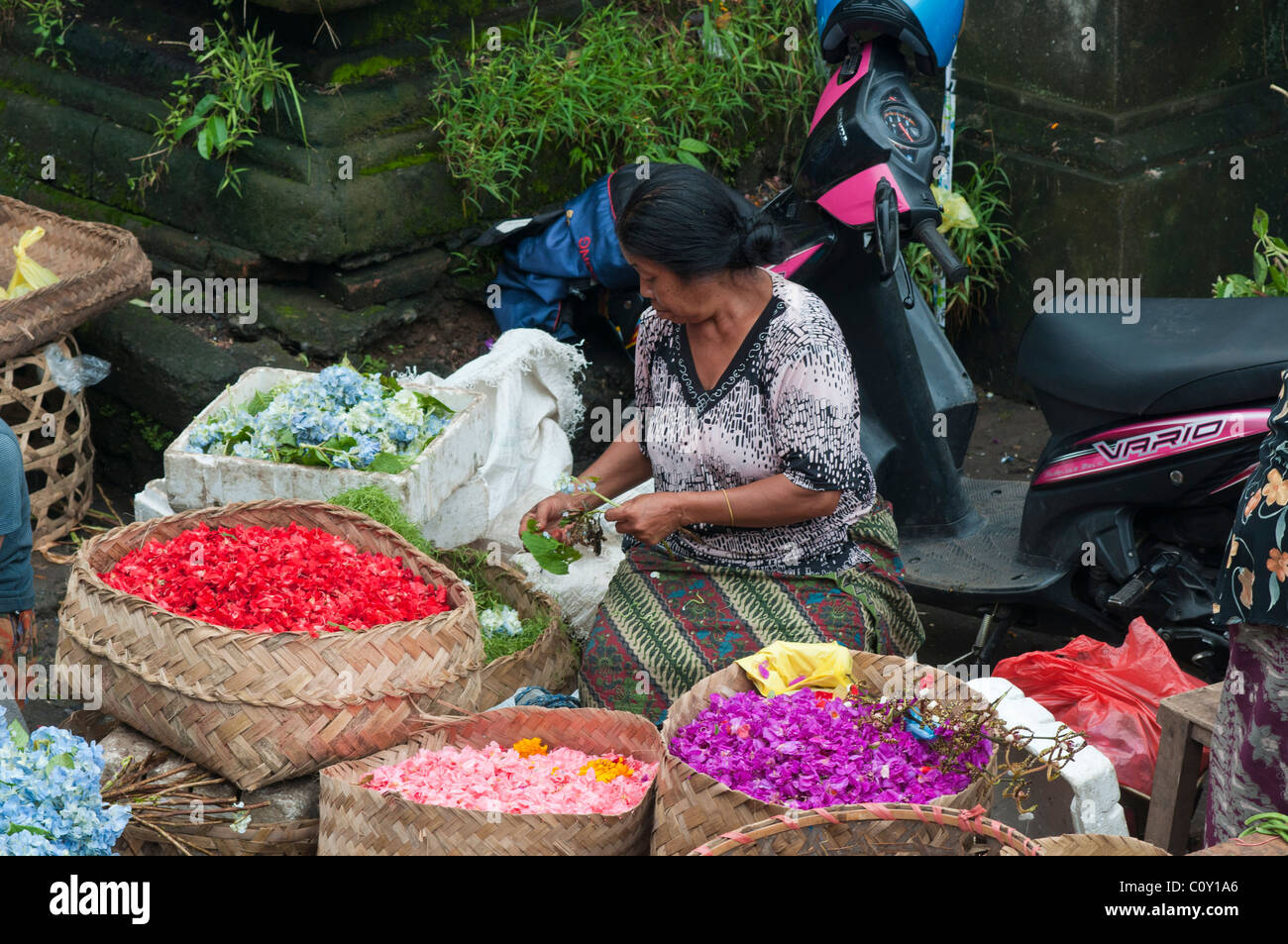 Donna vendita di petali di fiori per la realizzazione di offerte nel mercato in Ubud Bali Indonesia Foto Stock