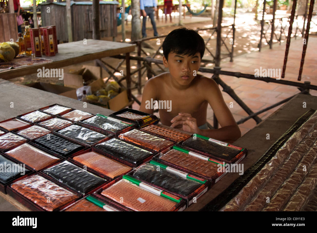 Giovane ragazzo vietnamita vendita falsi designer portafogli, Delta del Mekong, Vietnam Foto Stock