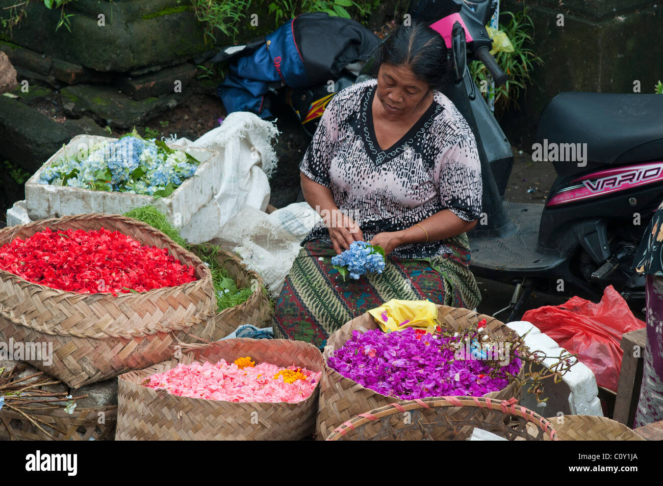 Donna vendita di petali di fiori per la realizzazione di offerte nel mercato in Ubud Bali Indonesia Foto Stock