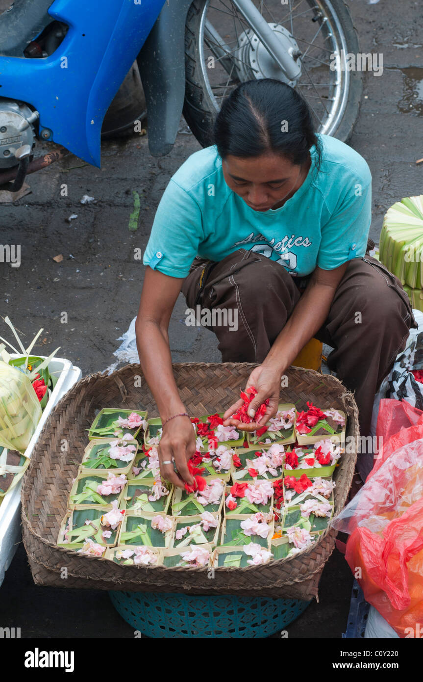 Donna vendita di petali di fiori per la realizzazione di offerte nel mercato in Ubud Bali Indonesia Foto Stock
