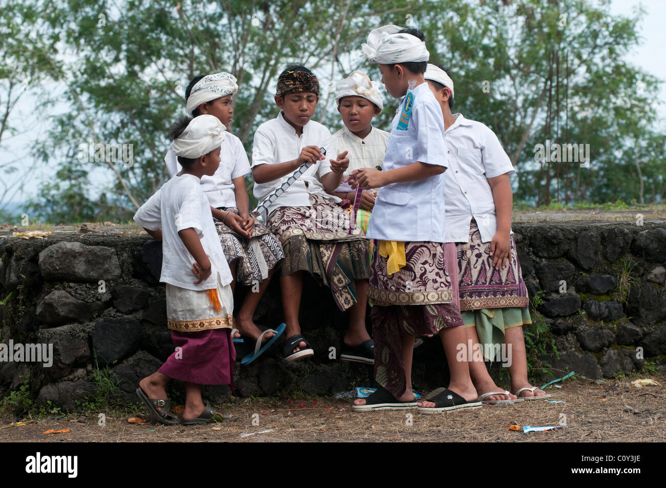 Giovani ragazzi balinesi vestiti per un festival religioso che suonano insieme in un festival del tempio a Padang Bai nella parte orientale di Bali in Indonesia Foto Stock