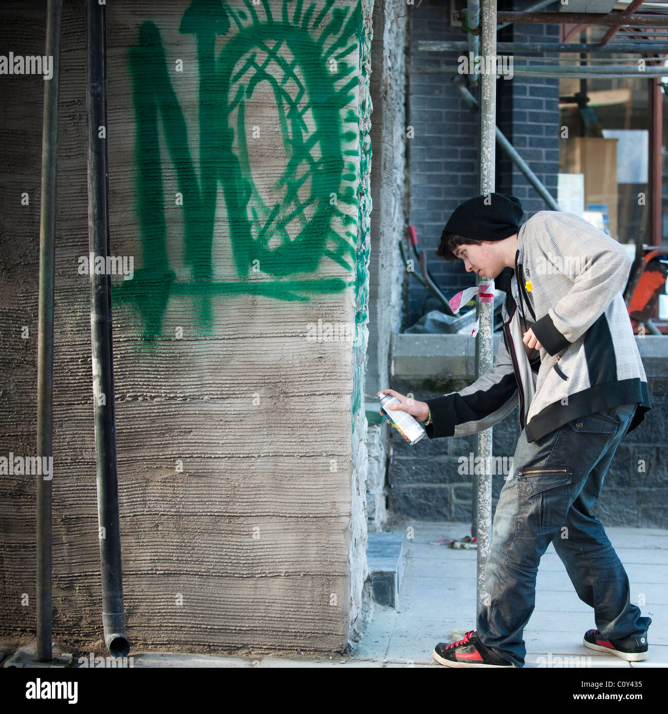 Un giovane ragazzo adolescente gioventù kid la spruzzatura di graffiti su un muro, REGNO UNITO Foto Stock